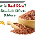A bowl of red rice on a wooden table with a spoon, showing healthy grains rich in fiber and antioxidants.