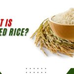 Wooden bowl filled with parboiled rice and rice stalks, highlighting the question what is parboiled rice.